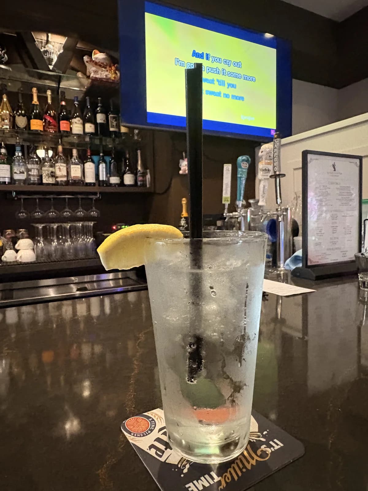 Wednesday karaoke night at Aya Golf Lounge — club soda at the bar with karaoke lyrics on the screen above