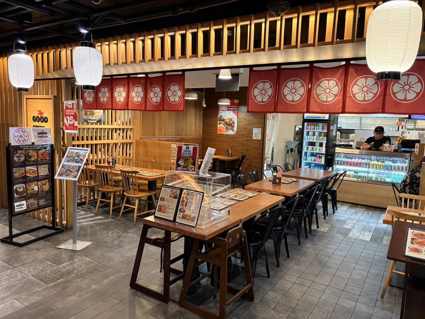 Good Chicken storefront inside Stix Asia food hall in Waikiki, with red noren curtains and a kamaʻāina discount sign